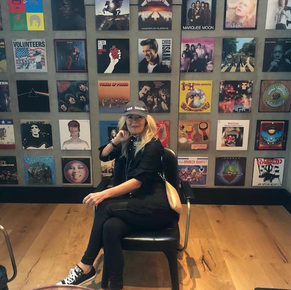 Anna Russo-Sieber and a wall of vinyl record cover art.